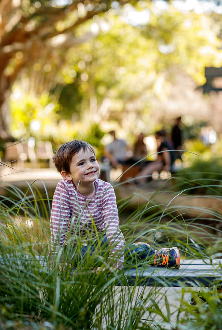 Smiling boy climbing bench and exploring the Garden