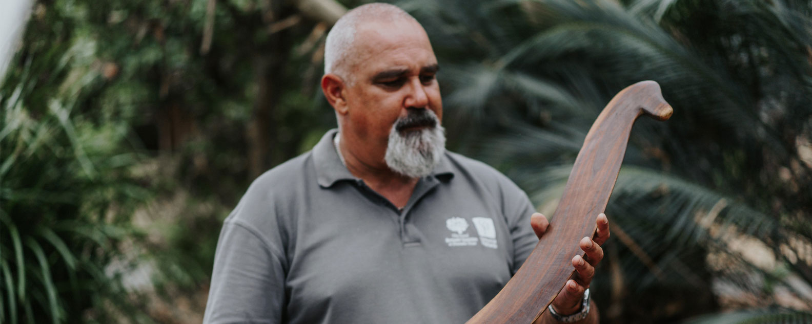 First Nations educator looking at a wooden tool