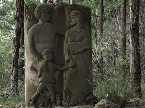 Sandstone Stolen Generations Memorial of a First Nations Family surrounded by trees by artist Badger Bates 