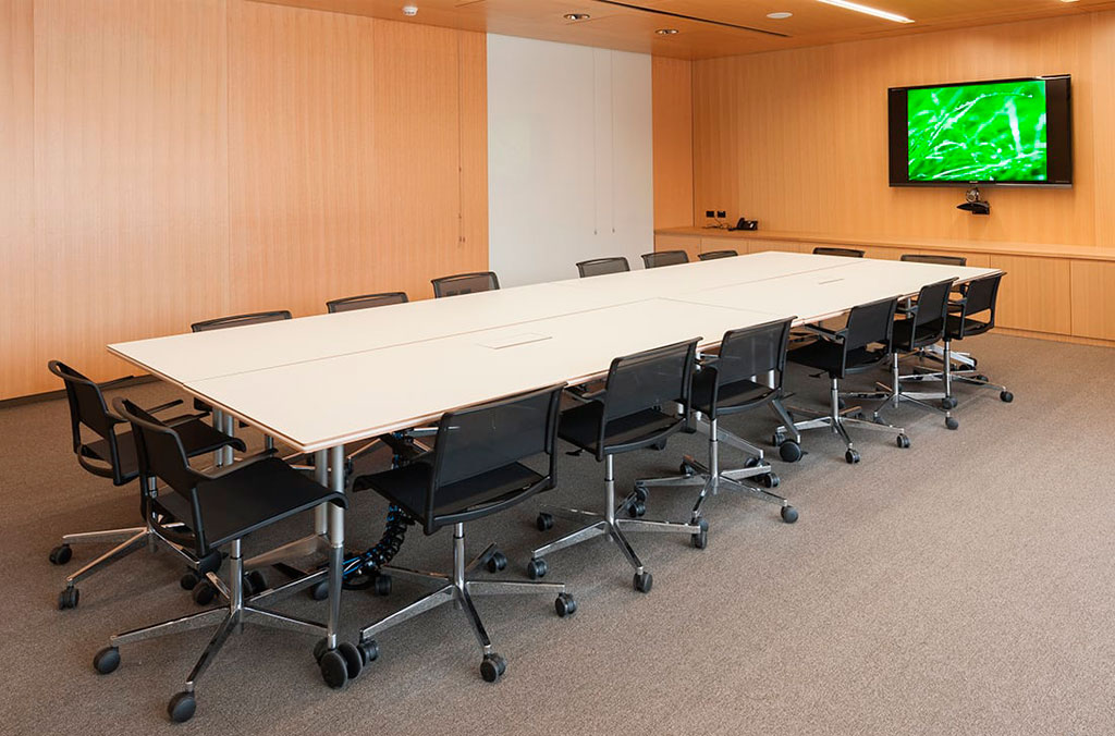 Meeting room with wood panelled walls, a long meeting table with seating and a flat screen