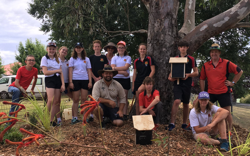 School students with educator showcasing their garden