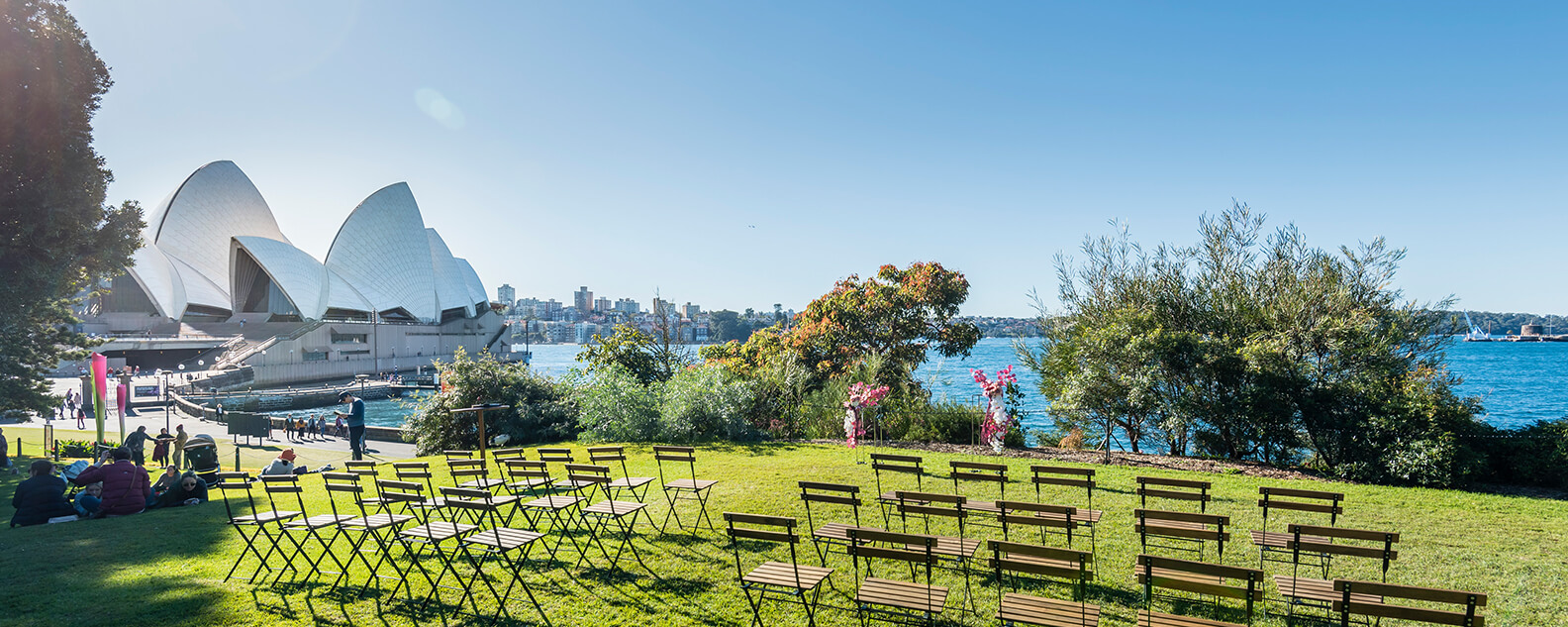 Chairs lined up on lawn, overlooking Sydney Harbour with view of Opera House