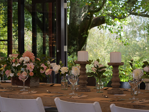 Table set with flowers, candles for a wedding, looking out glass doors to an idyllic garden
