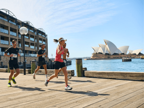 Runners jog along the Sydney Harbour front, with Opera House in background