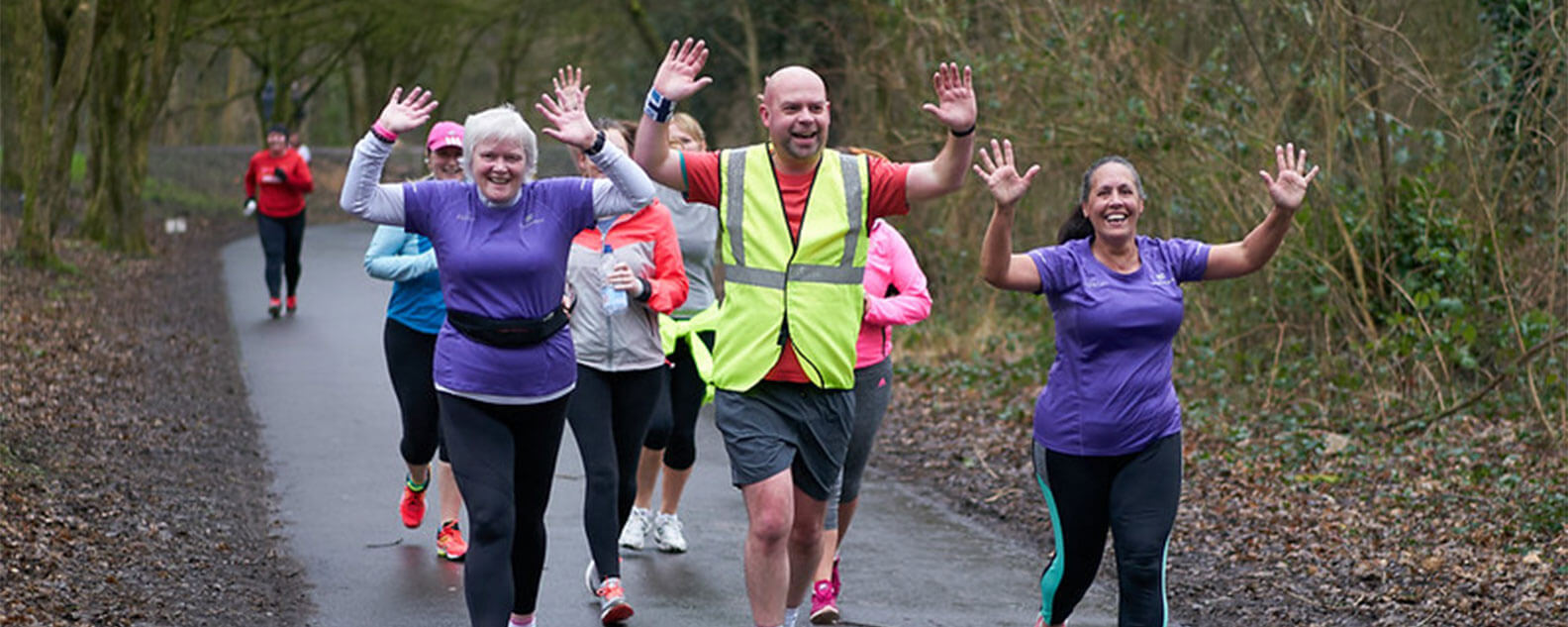 A group of people running, smiling and waving their hands