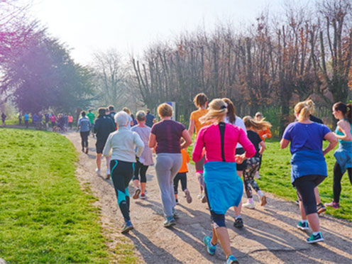 Group of people running outside in the sunshine