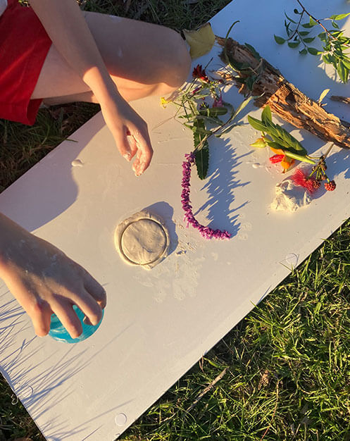 A person's hands working with clay and natural materials