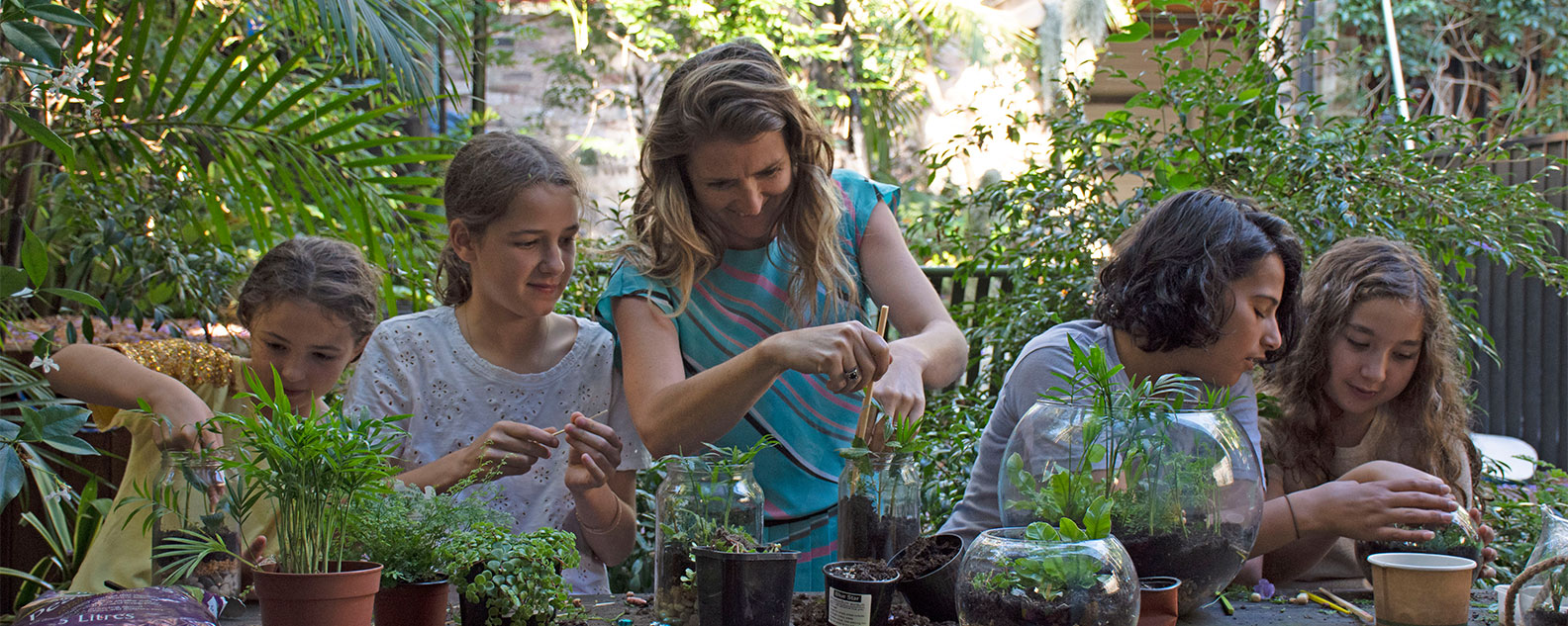 A family placing plants into a jar to create a terrarium