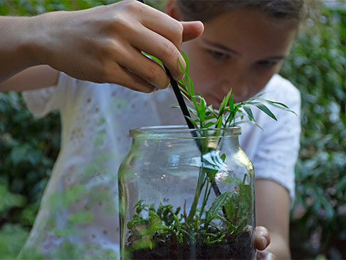 Girl placing plants into a jar