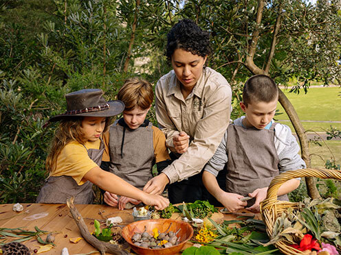 Three kids with an Educator making nature craft