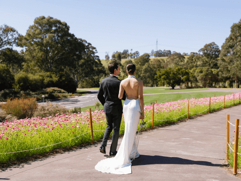 Two people walking down a garden path for their wedding