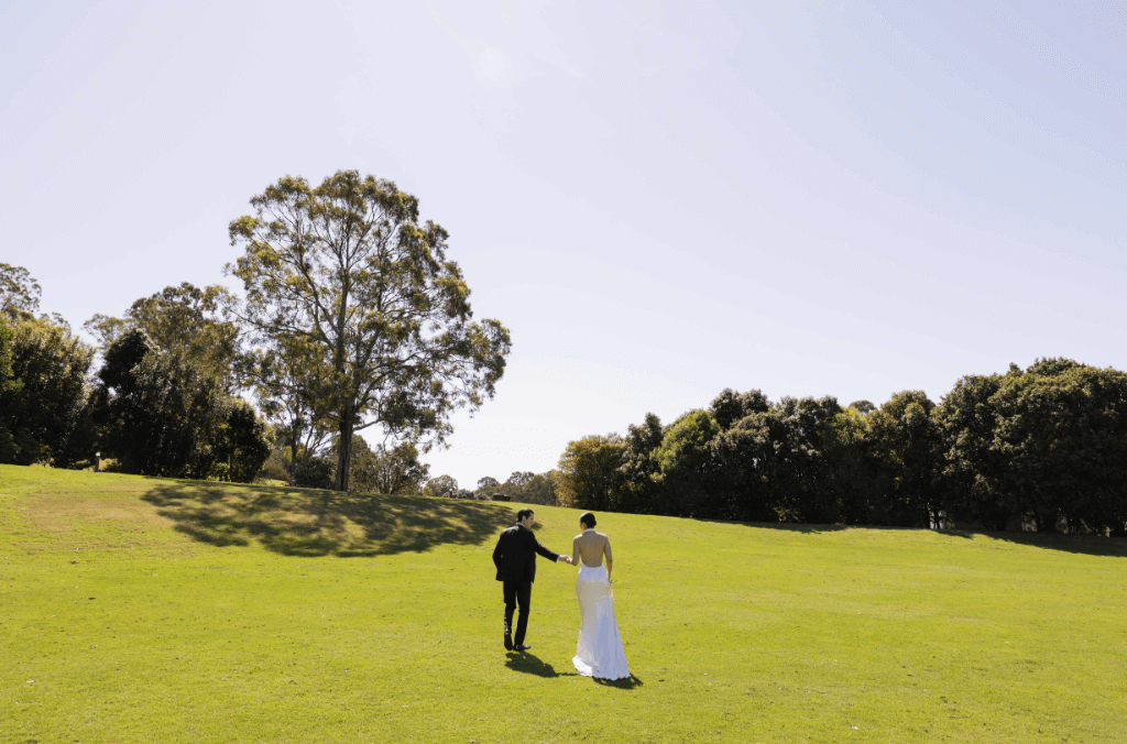 A wedding couple walking up a hill with trees