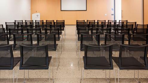 A wood panelled room with rows of chairs in front of a presentation screen