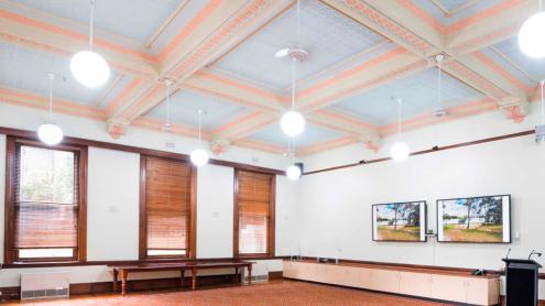 Renovated Victorian-era room with carpet, painted ceiling mouldings, wooden window frames and blinds.