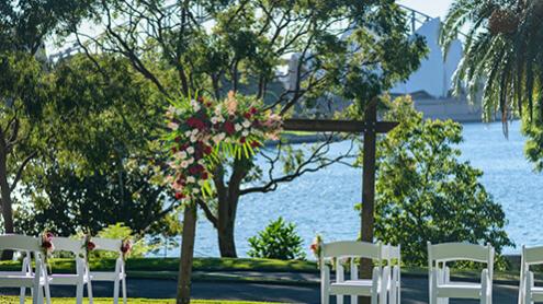 Lawn with wedding arch and white chairs, overlooking Sydney Harbour