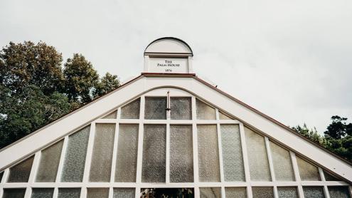 Glass roof of historic Palm House, with white panelling and sign 'Palm House'