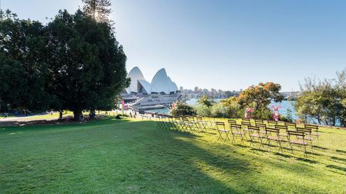 Chairs lined up on lawn, overlooking Sydney Harbour with view of Opera House