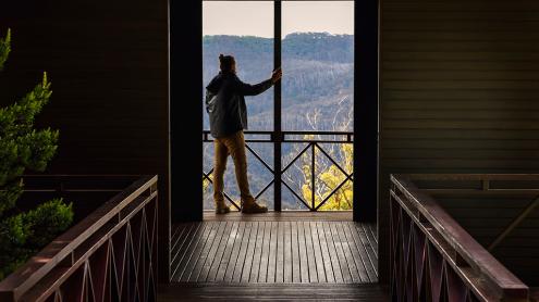 Person standing on deck of pavilion, looking towards mountains