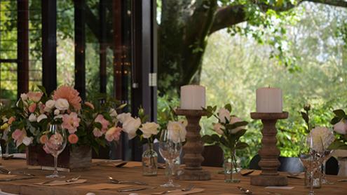 Table set with flowers, candles for a wedding, looking out glass doors to an idyllic garden