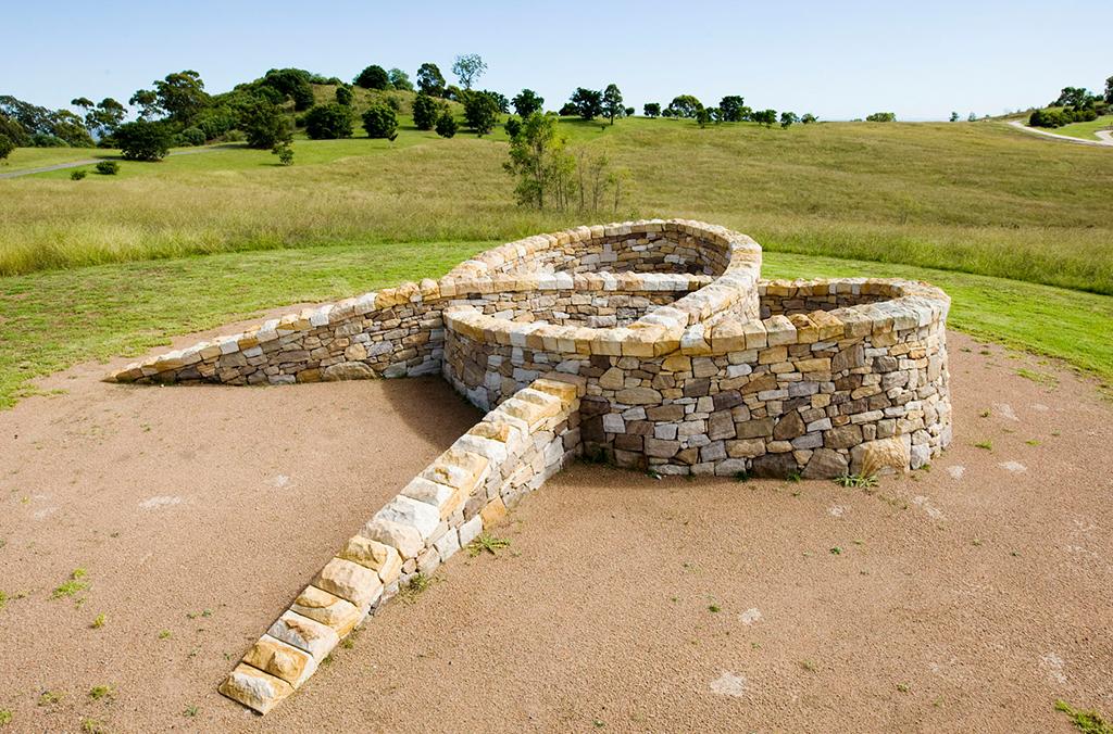 A stone sculpture of a knot, on a hill