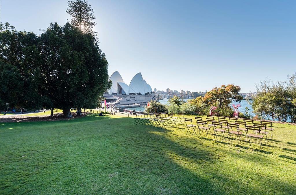 Chairs lined up on lawn, overlooking Sydney Harbour with view of Opera House