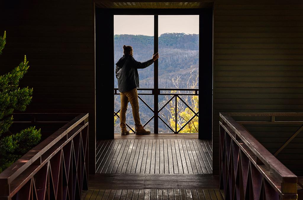 Person standing on deck of pavilion, looking towards mountains