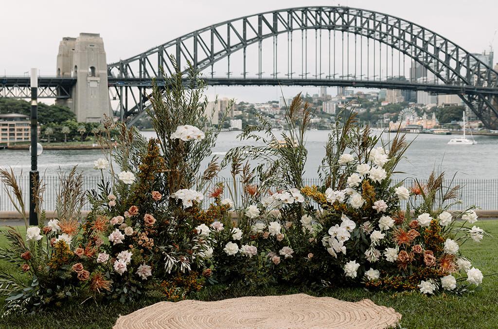 Flowers set up for a wedding ceremony, on a lawn overlooking Sydney Harbour Bridge