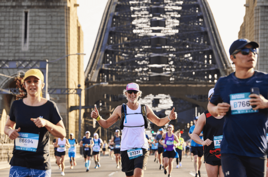 Joggers cross the Sydney Harbour Bridge, and give thumbs up