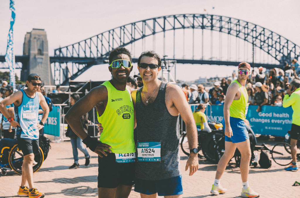 Two marathon runners pose for a photo in front of the Sydney Harbour Bridge