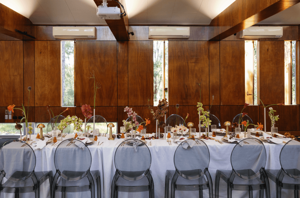 A long table dining wedding set up with florals, chairs and plates